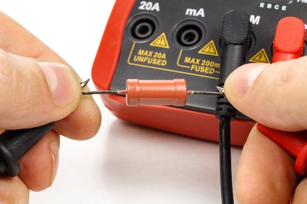 Multimeter testing a thermal fuse for continuity and resistance